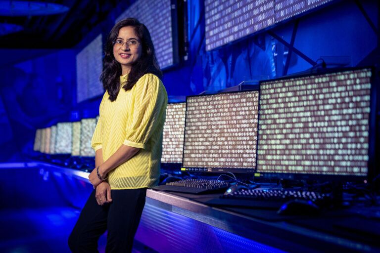 a woman in front of a line of computers covered in code
